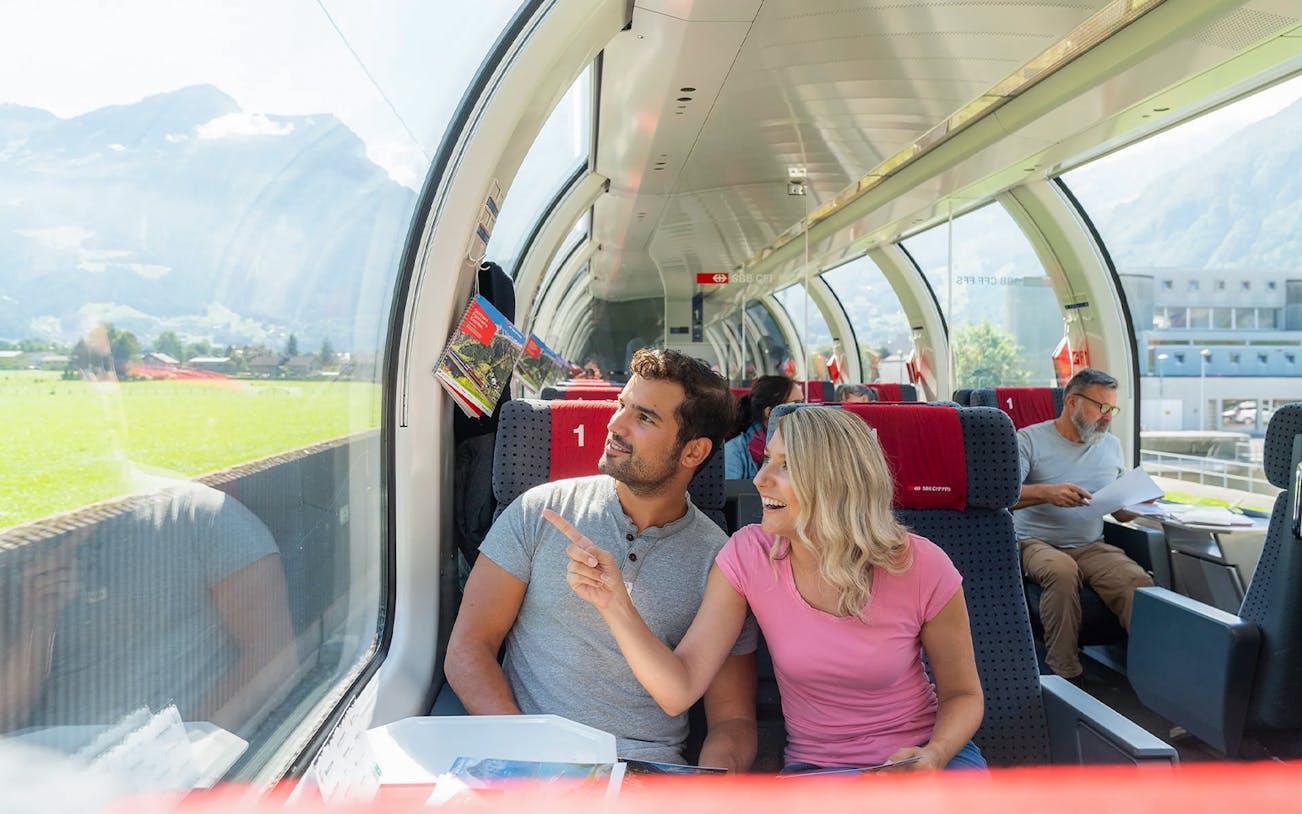 Couple enjoying scenic views on Gotthard Panorama Express train in Switzerland.