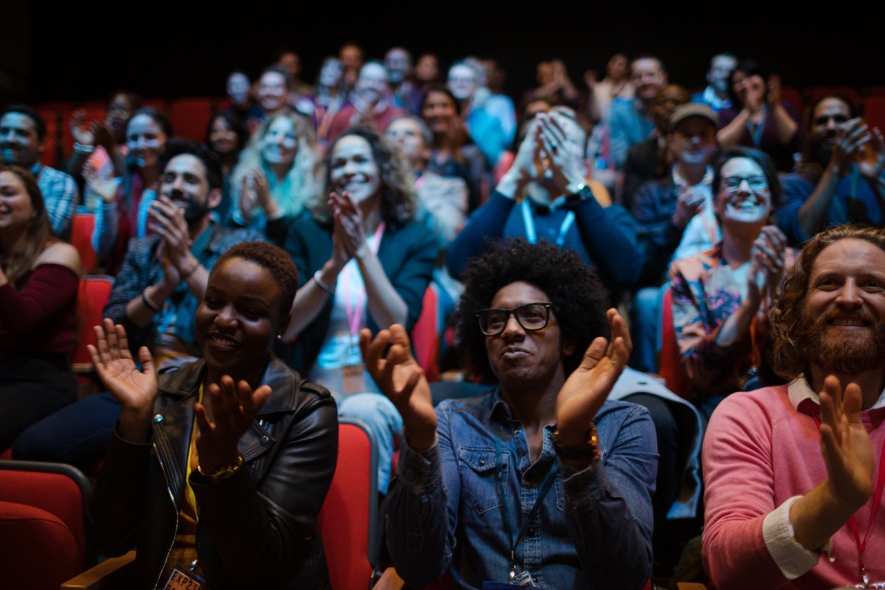Audience clapping and smiling during a live show.