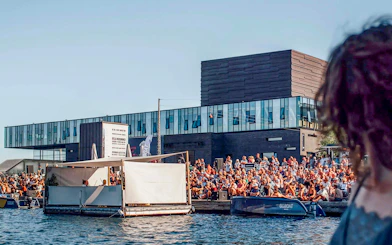 Crowd gathered by the water near The Playhouse in Copenhagen.