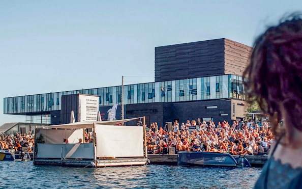 Crowd gathered by the water near The Playhouse in Copenhagen.