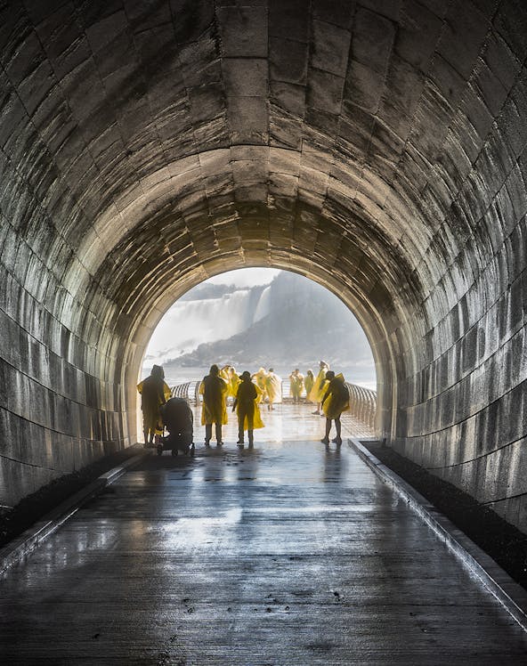 Visitors in yellow ponchos walking through Niagara Falls Tunnel towards the waterfall.