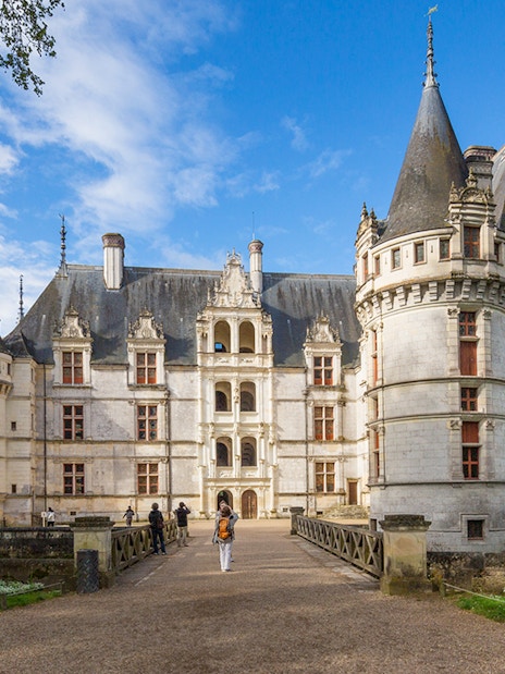 Chateau d'Azay-le-Rideau with visitors walking on the path, surrounded by gardens and trees.