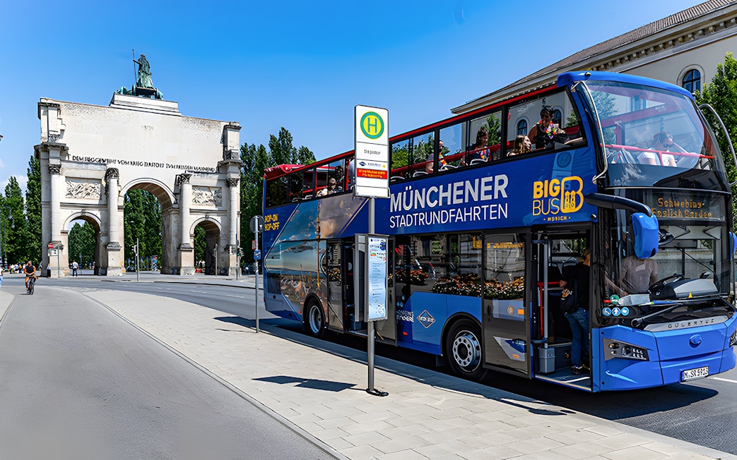 Tourists on Big Bus tour passing by Siegestor in Munich.