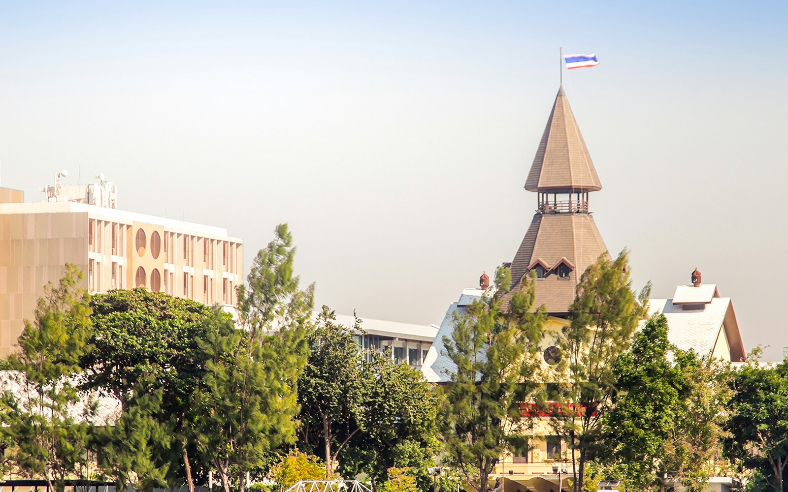 Thammasat University Tha Pachan campus with spire and trees viewed from Chao Phraya River.