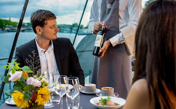 Server presenting wine to guests on a Seine River dinner cruise.