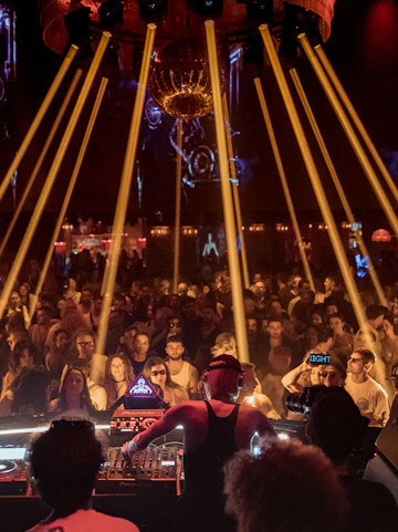 DJ performing at Club Chinois Ibiza with crowd and light show.