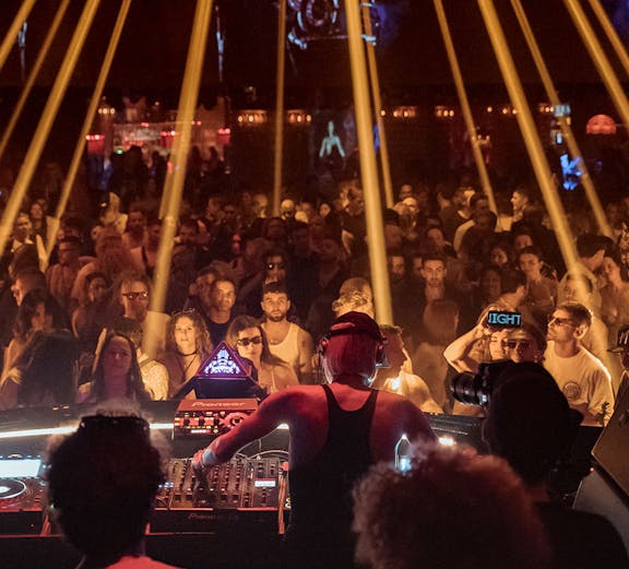 DJ performing at Club Chinois Ibiza with crowd and light show.