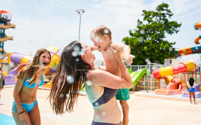 Family enjoying water play at Splash Island, Hurricane Harbour Arlington, with colorful slides in the background.