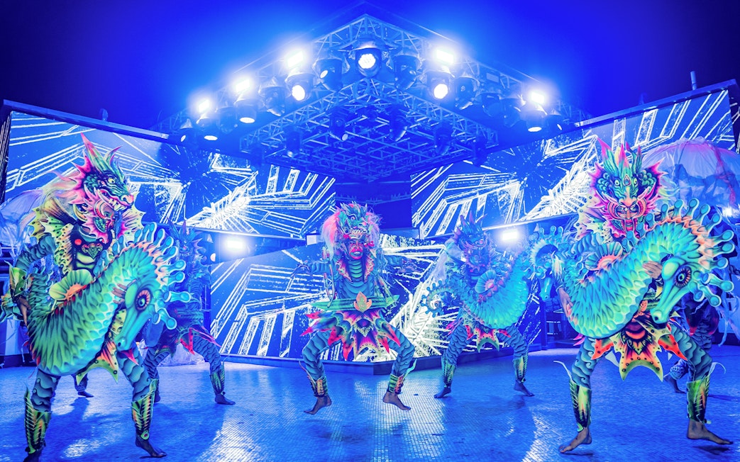 Performers in vibrant dragon costumes at Atlas Beach Club event.