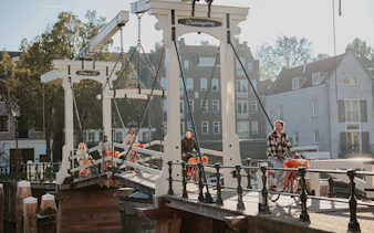Cyclists crossing a canal bridge on a city bike tour.
