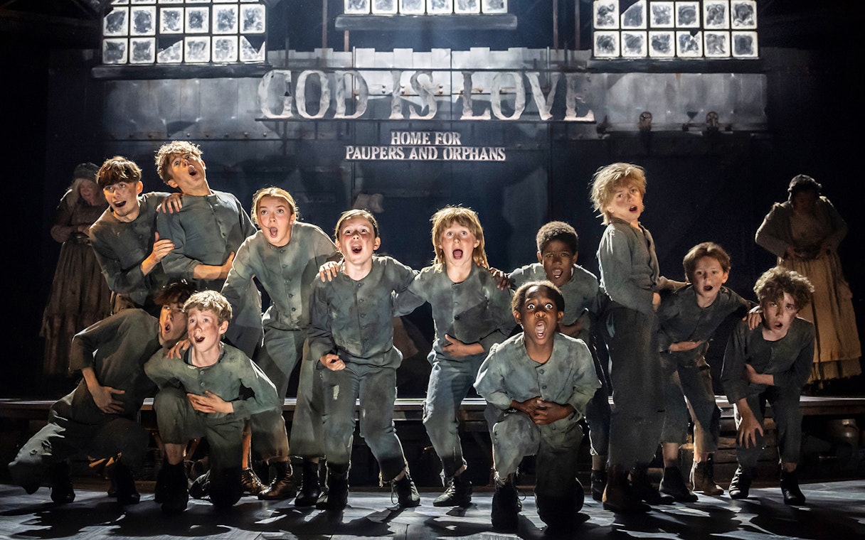 Children performing on stage in a scene from the musical Oliver!