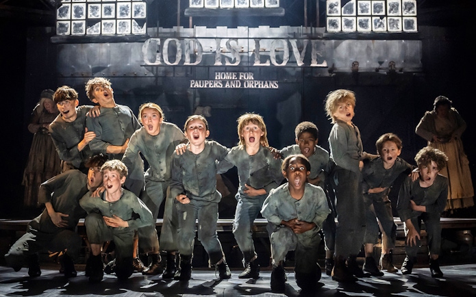 Children performing on stage in a scene from the musical Oliver!