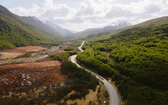 Winding road through Carbajal Valley with lush green forests and distant mountains, Ushuaia, Argentina.