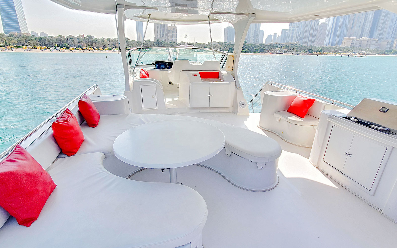 Luxury yacht deck with red cushions, Dubai skyline in background.
