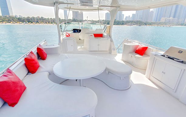 Luxury yacht deck with red cushions, Dubai skyline in background.