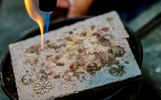 Filigree jewelry piece being crafted with a torch in Dorgali workshop.