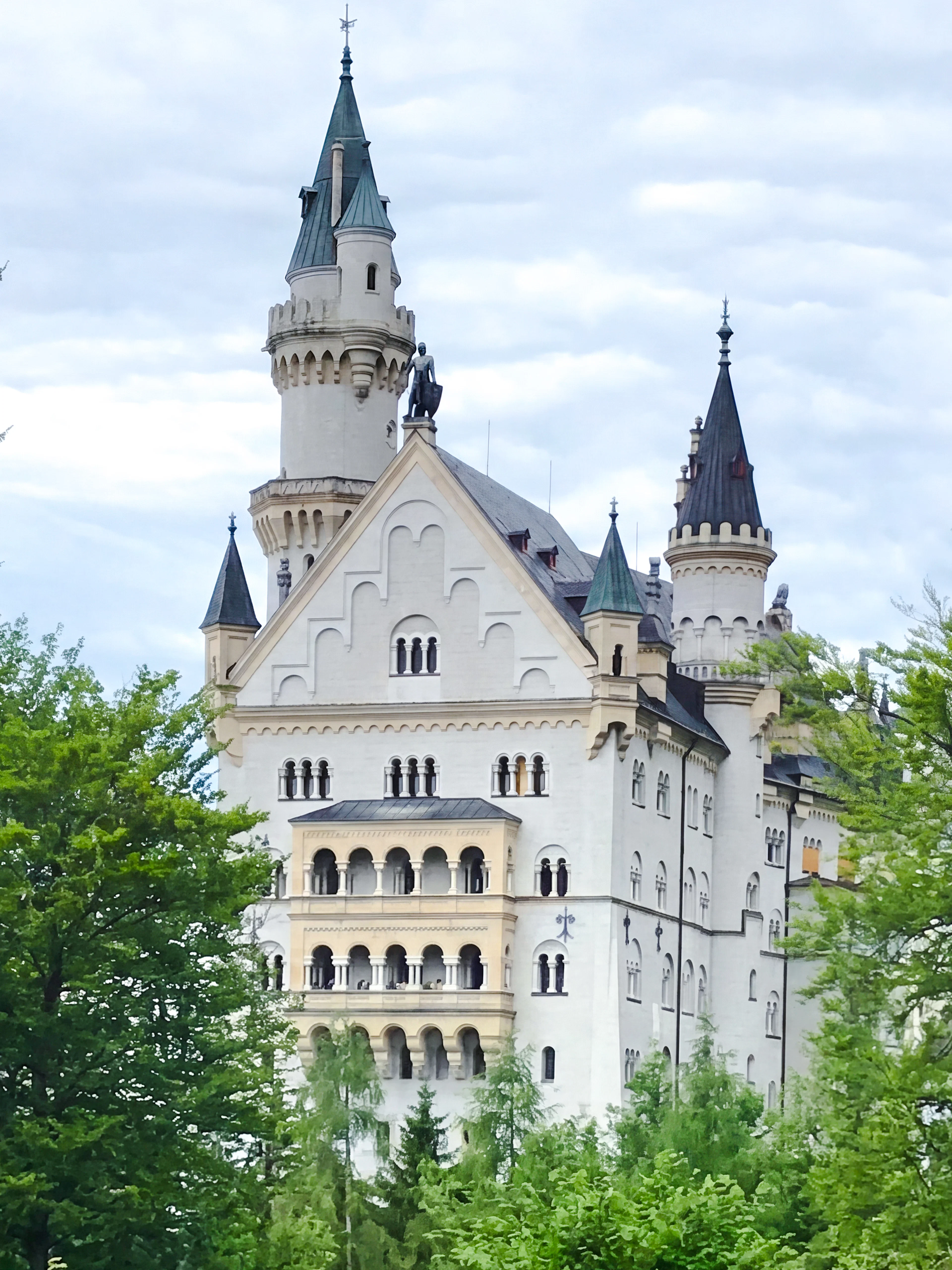 Neuschwanstein Castle surrounded by lush green trees in Bavaria, Germany.