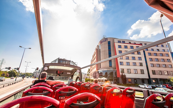 Open-top bus tour passing by Galaxy Hotel in Kraków.