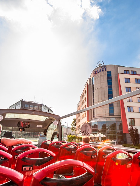 Open-top bus tour passing by Galaxy Hotel in Kraków.
