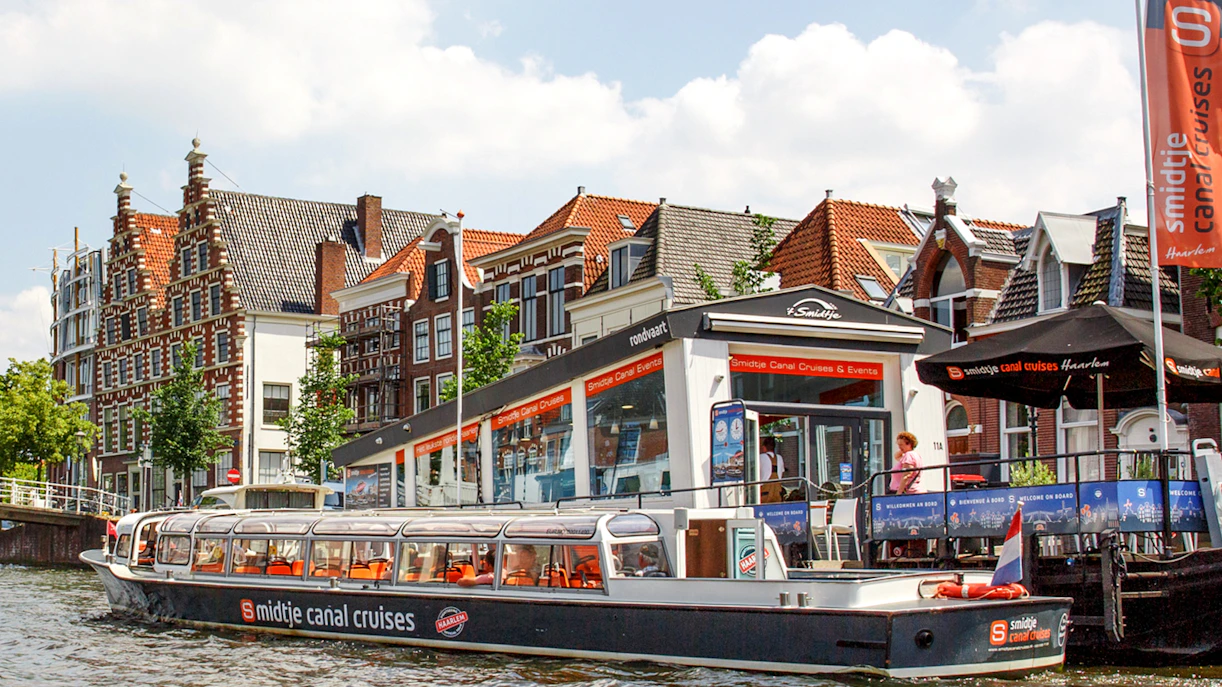 Haarlem canal cruise boat docked near historic Dutch buildings.