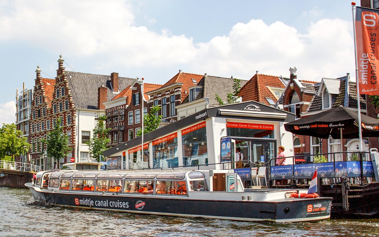 Haarlem canal cruise boat docked near historic Dutch buildings.