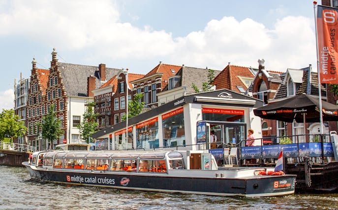 Haarlem canal cruise boat docked near historic Dutch buildings.