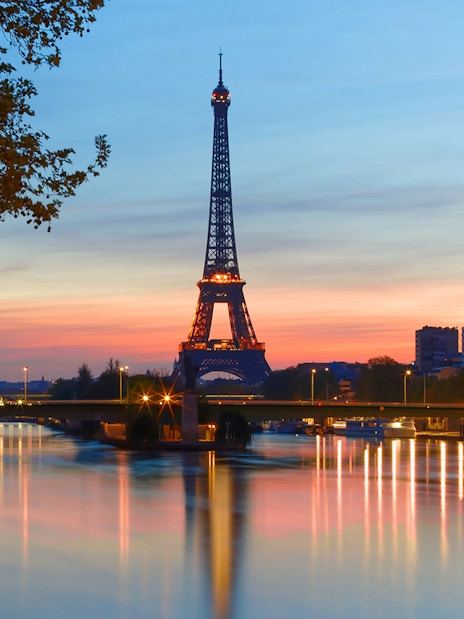 Eiffel Tower at sunset with Seine River reflections, Paris.