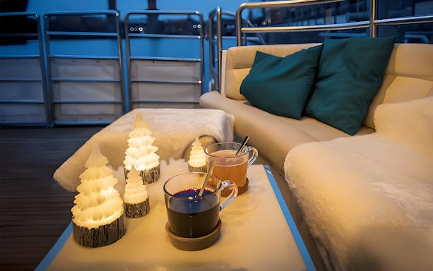Cozy seating with festive candles and drinks on a Berlin Christmas cruise.