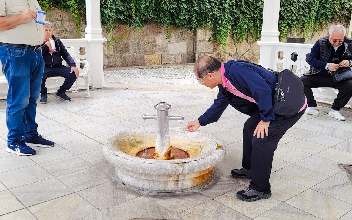 Man collecting water from mineral spring in Karlovy Vary.