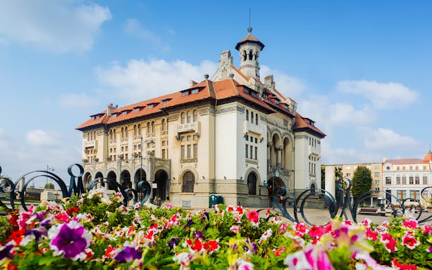 Constanta City Hall with colorful flowers in foreground on guided walking tour.