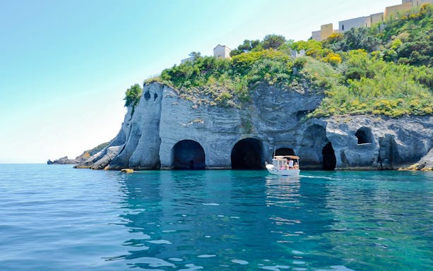 Boat near sea caves on Ponza Island during day trip from Rome.