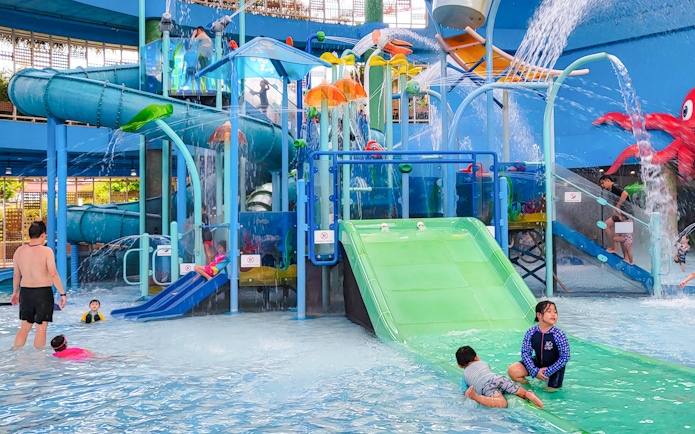 Kids playing on water slides at a splash park in Singapore.