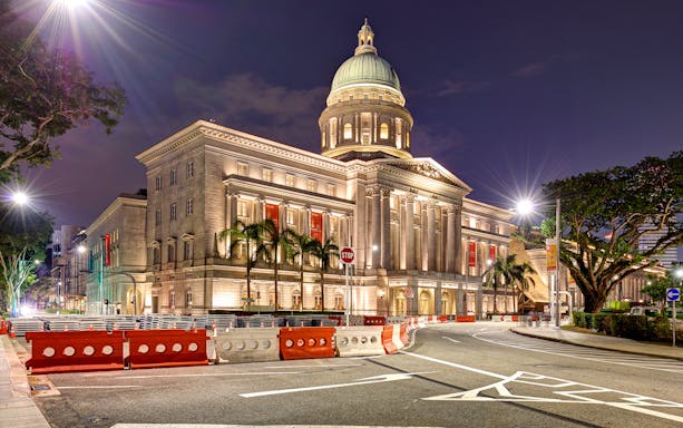 Singapore National Gallery illuminated at night with street view.