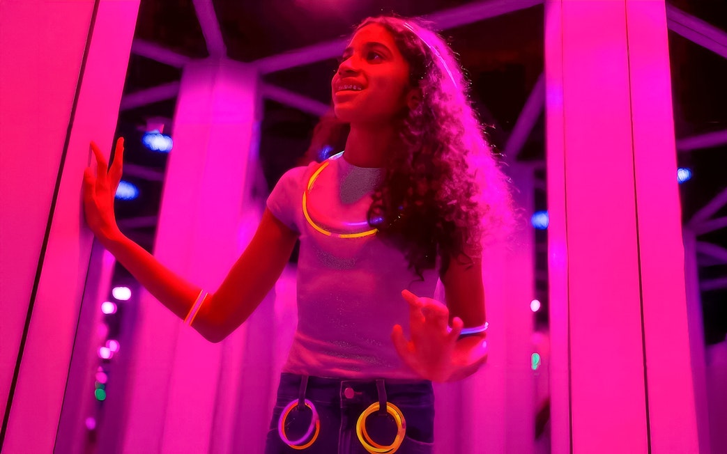 Kids exploring Mirror Maze at American Dream, surrounded by glowing lights.