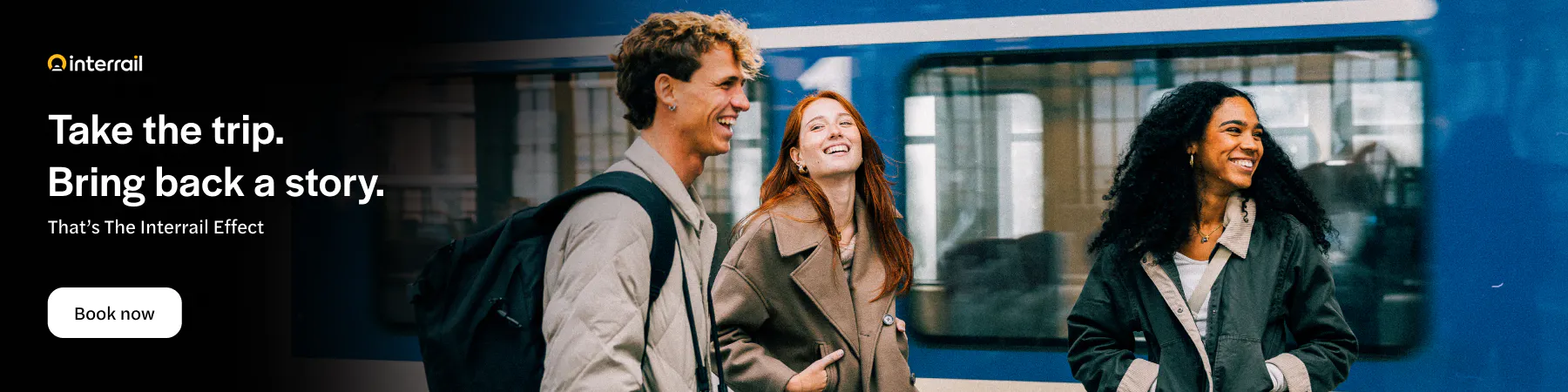 Three friends smiling in front of a blue train.
