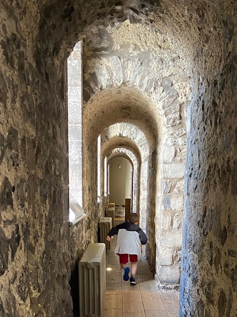 Stone corridor inside the Tower of London, early morning, with a child walking through.