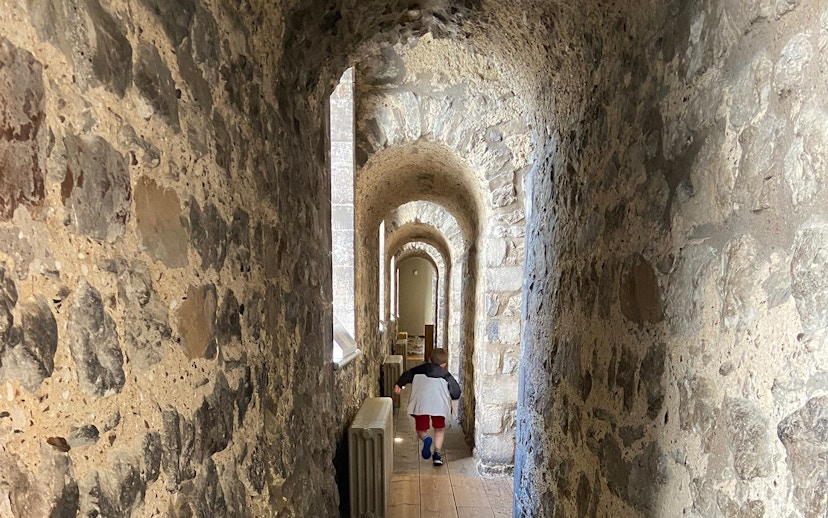 Stone corridor inside the Tower of London, early morning, with a child walking through.