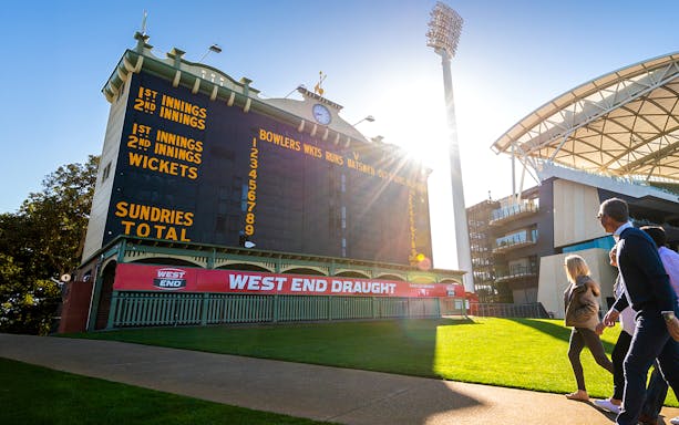 People walking past the historic scoreboard at Adelaide Oval Stadium.