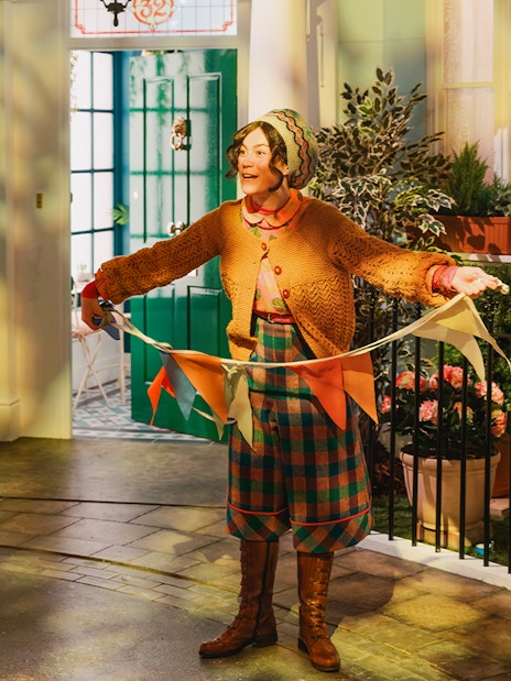 Tour guide holding colorful flags at The Paddington Bear Experience in London.