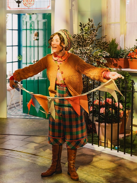 Tour guide holding colorful flags at The Paddington Bear Experience in London.