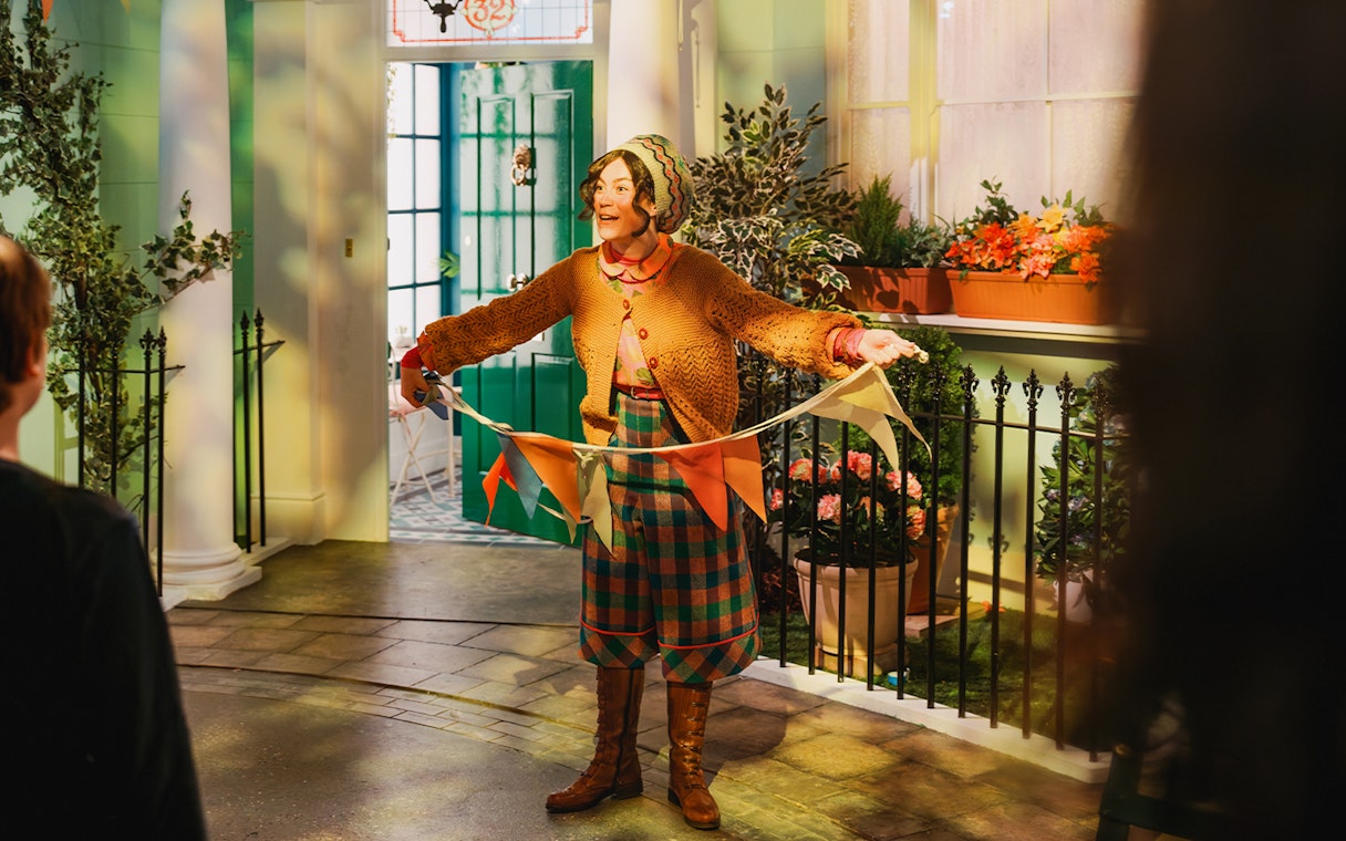 Tour guide holding colorful flags at The Paddington Bear Experience in London.