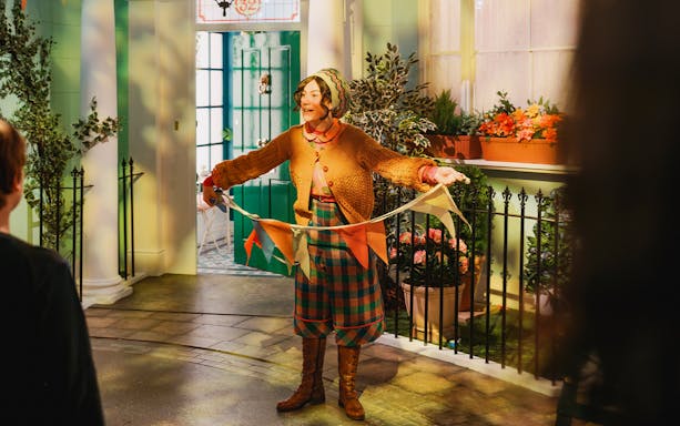 Tour guide holding colorful flags at The Paddington Bear Experience in London.