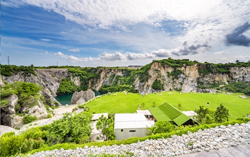 Green lawn and rocky cliffs at LOF LAND with visitors exploring the scenic landscape.