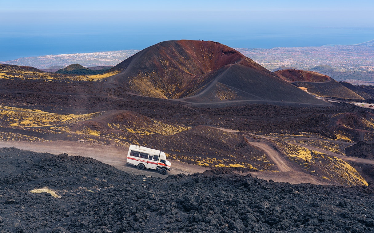 4x4 mini bus driving on volcanic terrain at Mount Etna, Sicily.
