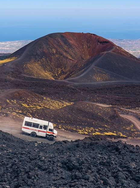 4x4 mini bus driving on volcanic terrain at Mount Etna, Sicily.