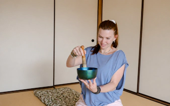 Person using a singing bowl during a Japanese sound bath session in Kyoto.