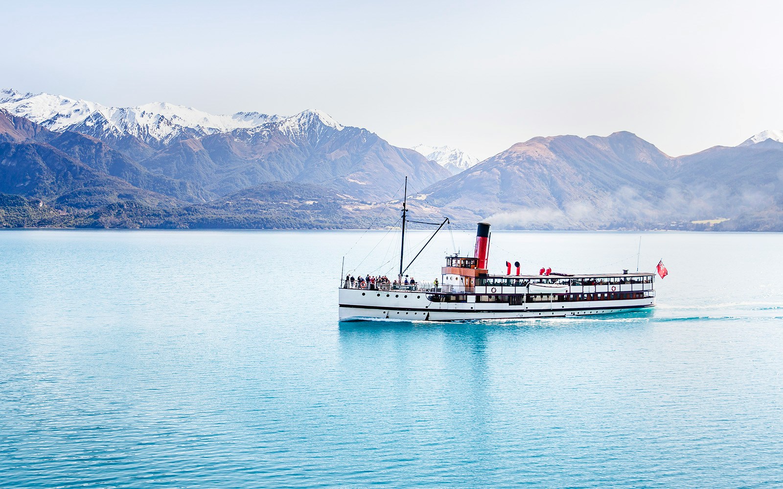 Steamboat cruising on Lake Wakatipu with snow-capped mountains in the background.