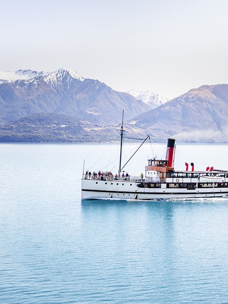 Steamboat cruising on Lake Wakatipu with snow-capped mountains in the background.