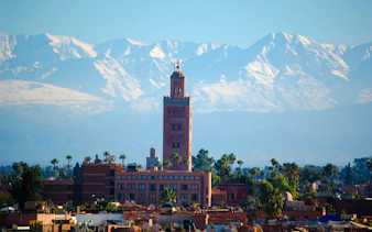 Koutoubia Mosque with Atlas Mountains in Marrakech, Morocco.