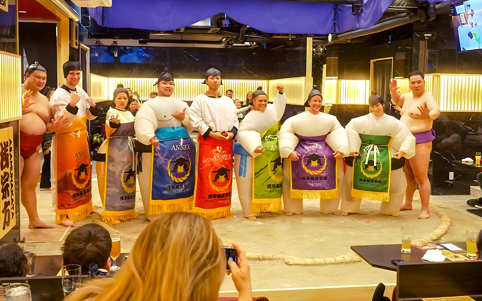 Visitors posing with sumo wrestlers at Asakusa Sumo Club, Tokyo.